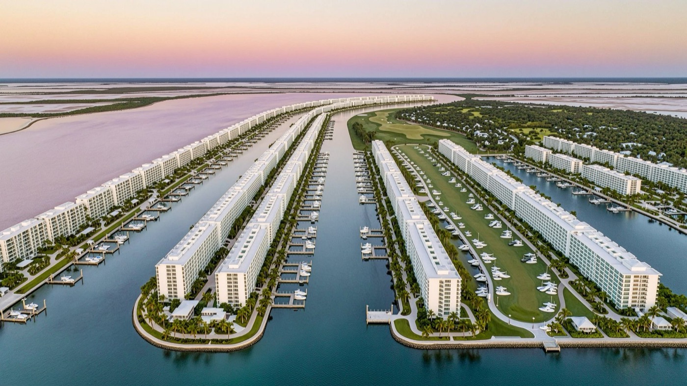 An aerial view at dusk of long white apartment blocks on engineered peninsulas, private boat slips along every channel, a golf course between them, and a pale pink lakebed on the horizon.